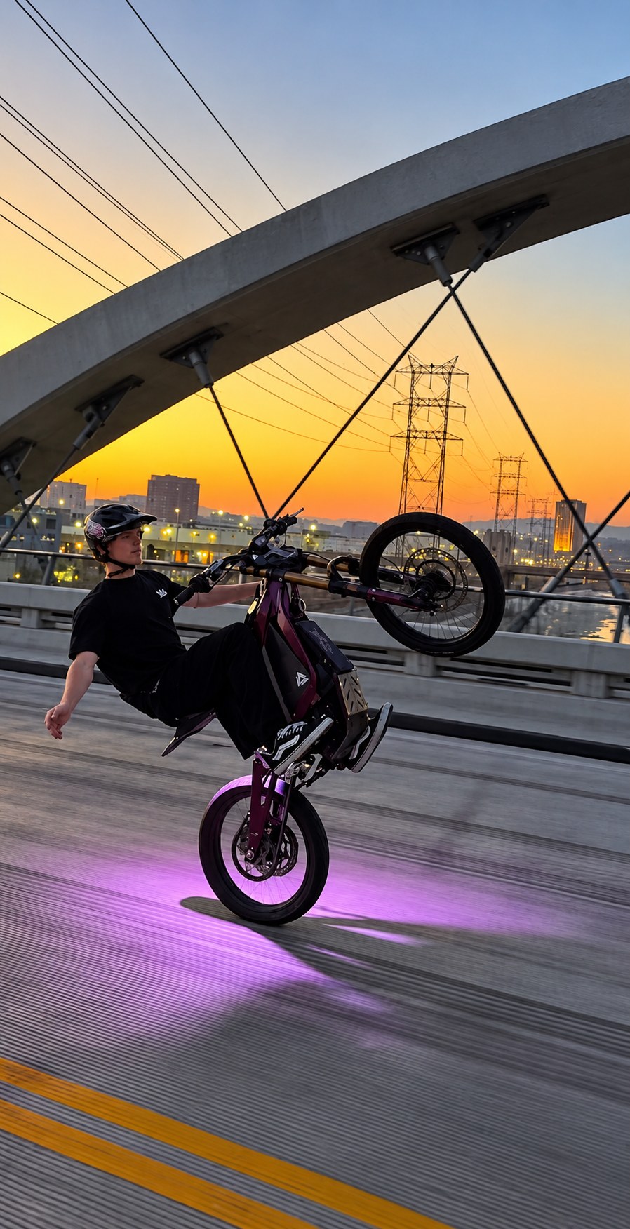 EXZ MOTO rider doing a wheelie on an e-moto on a bridge at sunset